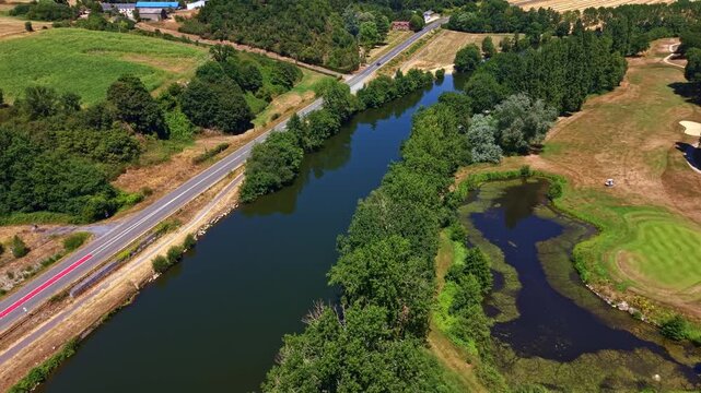 Drone flying above the Mayenne River beside a rural golf course and countryside in western France.