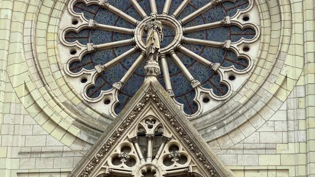 Tilt-up shot revealing the ornate rose window and Gothic stone details of Saint Joseph Church in Angers.