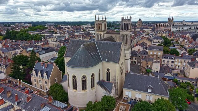Drone pulling back and ascending behind Saint Joseph Church, revealing the historic cityscape of Angers from above.