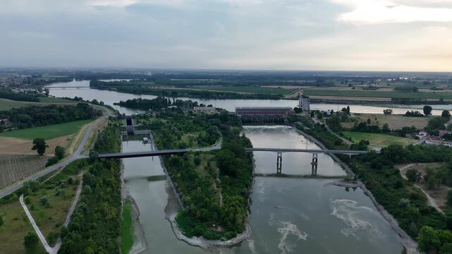 Isola Serafini hydroelectric complex near Monticelli d'Ongina, Piacenza, Emilia-Romagna, Italy, reveals powerhouse, diversion channels, control structures and low Po River flow, drone forward flyover.