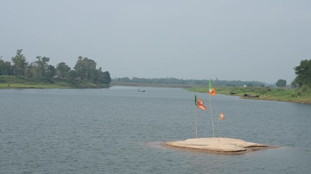 Flags of Indian political parties are being hoisted on the river sandbar.