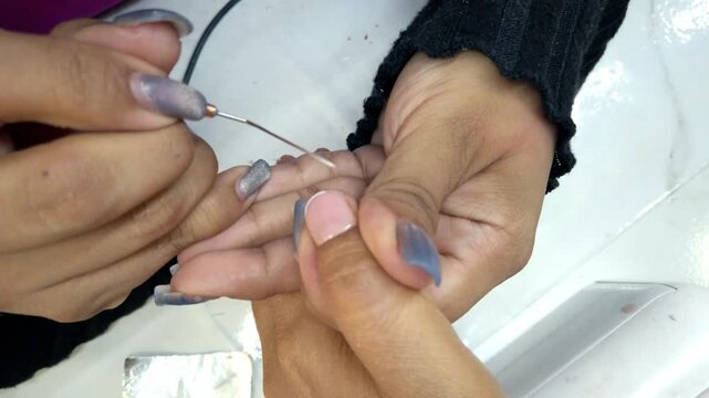 Closeup of beautician removing cuticle with precision tool during professional manicure treatment, showcasing detailed hand care at beauty salon in Mexico