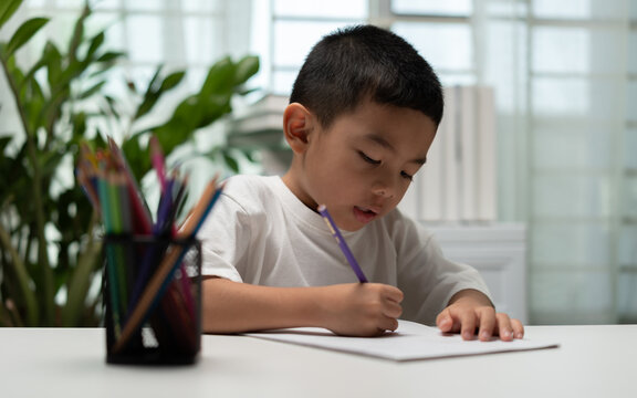 Young child practicing handwriting with a pencil at home, supporting early education, literacy, concentration, fine motor skills, learning, childhood development, and academic preparation.