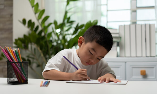 Young child practicing handwriting with a pencil at a study desk, promoting early education, literacy, concentration, fine motor skills, cognitive development, homeschooling, and childhood learning.
