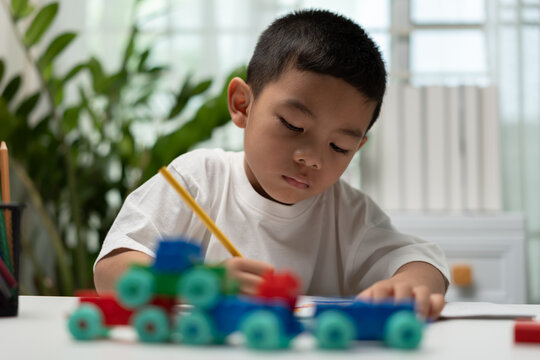 Young child practicing writing with a pencil while educational wooden toys rest nearby, highlighting early learning, creativity, literacy, concentration, cognitive development, and preschool education