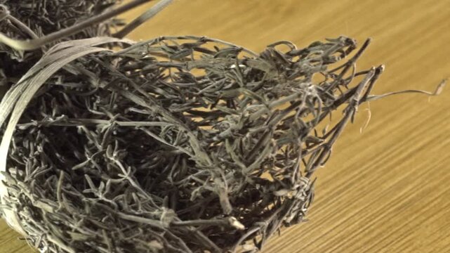 Macro close up of dried herb bundles tied with natural fiber showcasing natural texture and traditional preparation on wooden surface in indoor setting, Mexico.