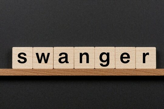 Wooden blocks spell out the word swagger on a shelf. Isolated letters form an inscription on a dark background, representing confidence and style.