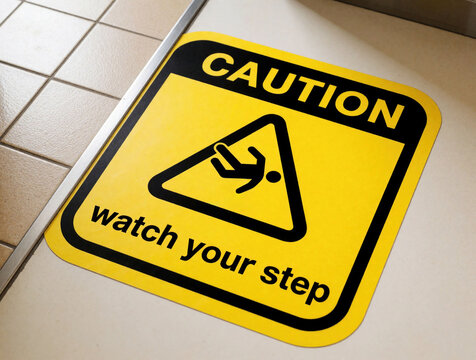 Yellow, black sticker sign on floor warns people to watch step. Hazard alert icon prevents falls on stairs uneven levels. Safety notice provides information about risk in construction area office