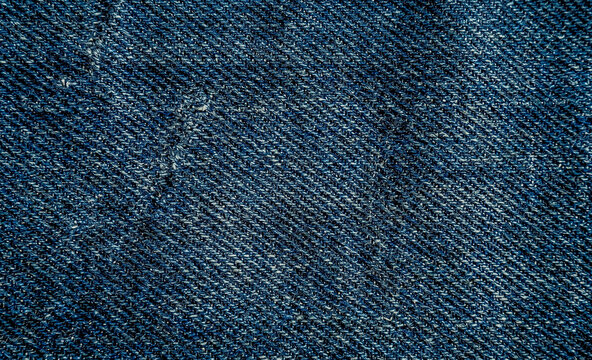 A close-up view of a textured denim fabric showcasing the intricate weave and deep blue hues typical of high-quality jeans.