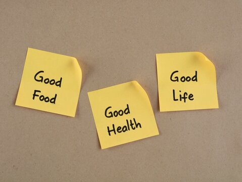Yellow adhesive notes with handwritten text good food, good health, and good life placed on a brown paper background. Concept for healthy lifestyle, wellness, diet motivation, and positive living