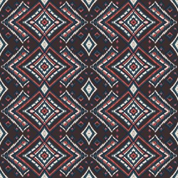 Seamless ethnic ikat pattern with vibrant orange and yellow geometric diamond motifs on a dark brown background. Bold tribal fabric design perfect for bohemian prints, wallpaper, and creative decor.