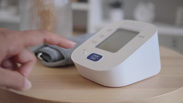 Person Pressing Start Button on Digital Blood Pressure Monitor