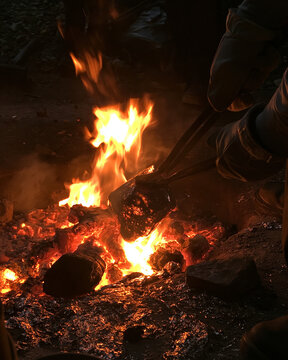 <Blacksmith Artisanship: Forging Metalwork with Fire, Flames, and Hot Coals in a Traditional Outdoor Workshop>