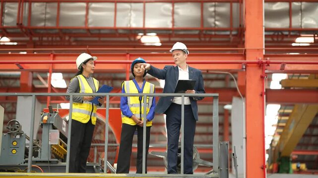 Engineers and factory manager reviewing production line from elevated platform, manufacturing workflow, industrial inspection, engineering teamwork, factory management.