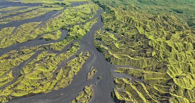 Ambrym Island in Vanuatu showcasing raw volcanic landscape with vast black ash fields contrasting against vibrant green rugged vegetation and unique geological formations shaped by past eruptions.