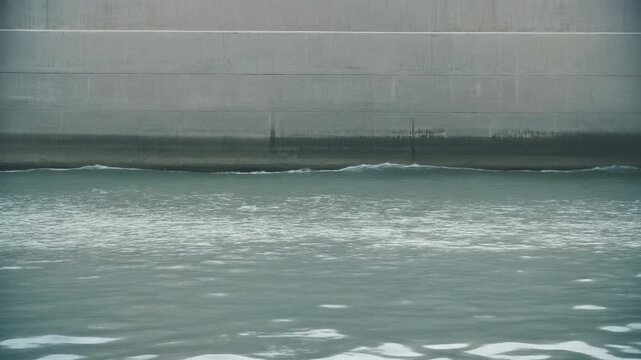 Clean concrete seawall with elevated water level for corporate ESG reports, environmental sustainability websites, and climate change presentations.