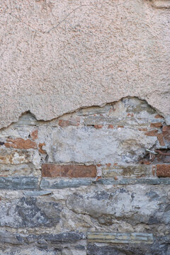 Weathered wall shows layers of stone and brick in an old building, revealing signs of wear over time