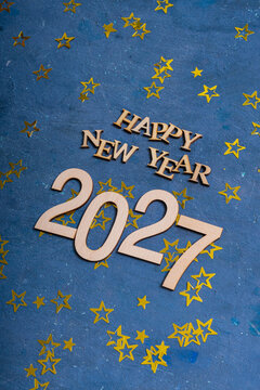New year 2027 celebration with wooden letters and golden stars on a blue background for a festive occasion