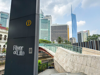 Obraz premium Kuala Lumpur, Malaysia - April 14, 2026: River of Life Sign Post with Merdeka 118 Tower and Pedestrian Bridge