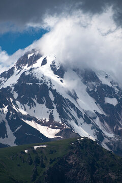 Vertical view of high Mount Kazbek peak with storm clouds and snow in Georgia with copy space