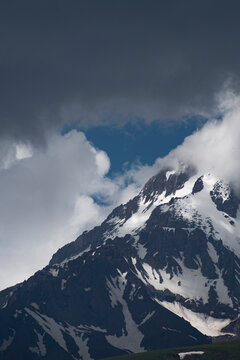 High Mount Kazbek slopes under dark storm clouds with blue sky patch in Georgia with copy space