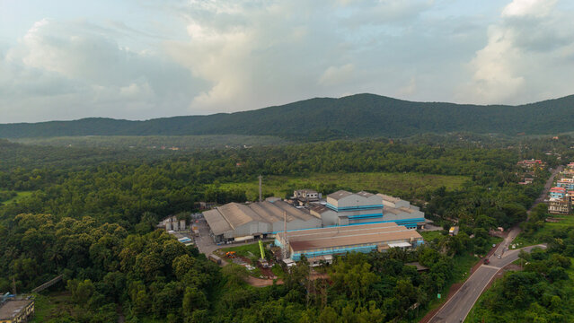 Tyre manufacturing plant with long production sheds set against forested mountain terrain