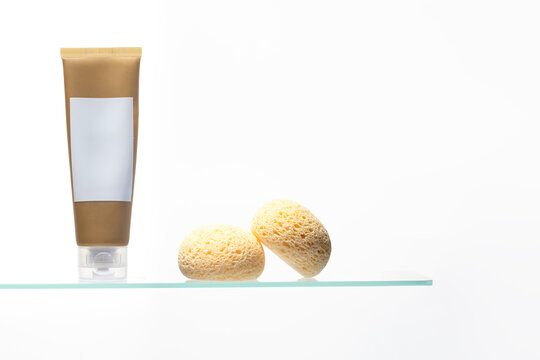 Close-up studio shot of a cream tube and exfoliation tools. The warm colors and white space are perfect for advertising organic, paraben-free, or vegan cosmetic lines.