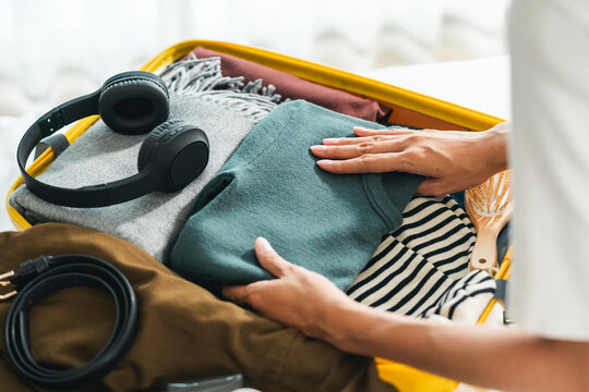 Happy Beautiful woman to folding her clothes pack suitcase for travel in holiday. Young female folding clothes while packing luggage at home.