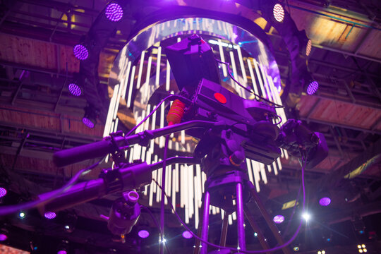 Professional broadcasting video camera on tripod with purple neon stage lights with copy space