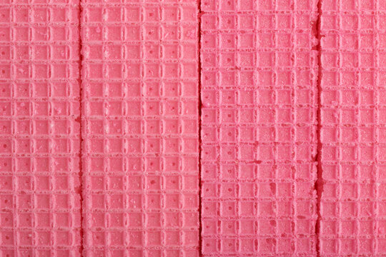 Close-up top view texture of crisp pink strawberry wafer biscuits arranged side by side.