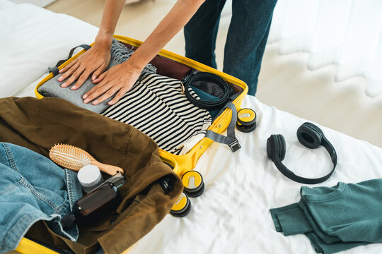 Happy Beautiful woman to folding her clothes pack suitcase for travel in holiday. Young female folding clothes while packing luggage at home.