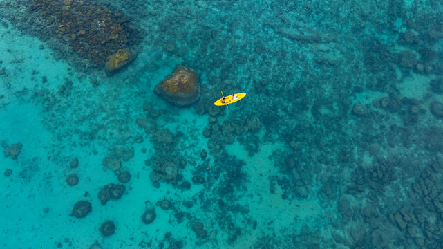 Aerial view of a woman and a young man kayaking on clear blue waters at Andaman Island. She does water sports activities.	