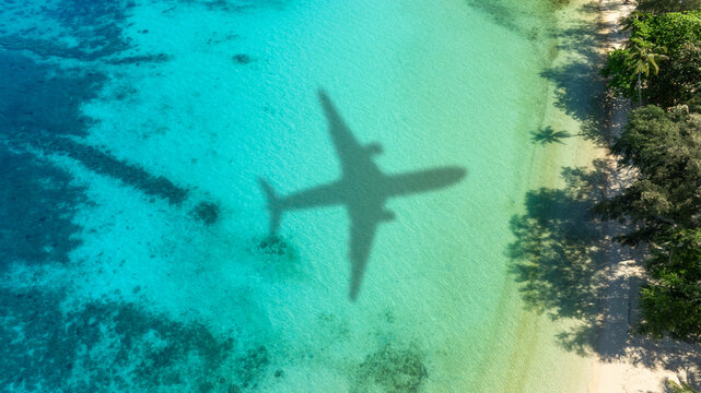 Aerial view of shadow passenger plane silhouette and sandy beach blue sea with waves at sea beach summer vacation sea travel concept	