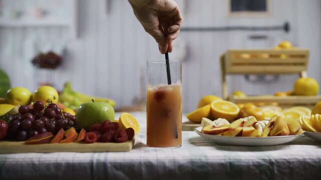 Woman's hand stirring drink mix while surrounded by delicious fresh fruit - medium shot in slow motion