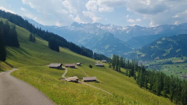 Panoramic view over alpine houses near Lenk in the Bernese Oberland, Switzerland, surrounded by lush summer meadows and greenery, leading toward hiking trails to F&auml;rmelberg