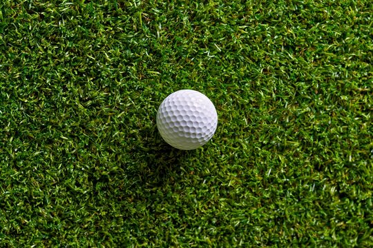 White golf ball rests on vibrant green grass. 64k 8k widescreen, HDR