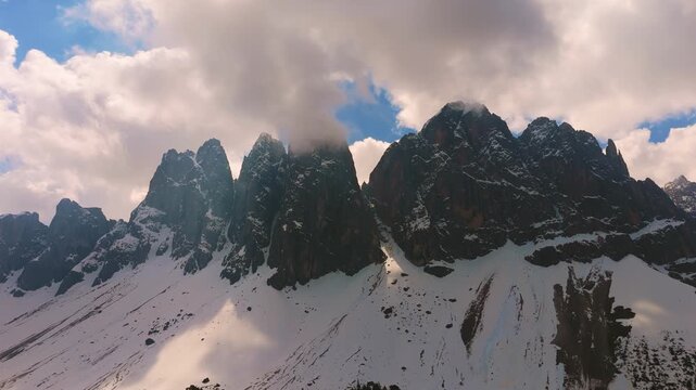 Towering Odle mountain peaks in Puez-Geisler Nature Park, Dolomites with snow. Low angle aerial view