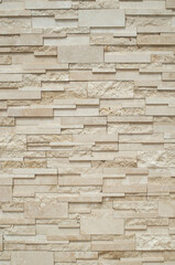 Fototapeta premium Modern relief decorative stacked stone wall cladding texture in beige tone