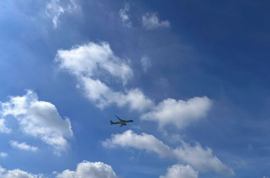 Commercial airplane flying through a blue sky with white clouds during daytime travel