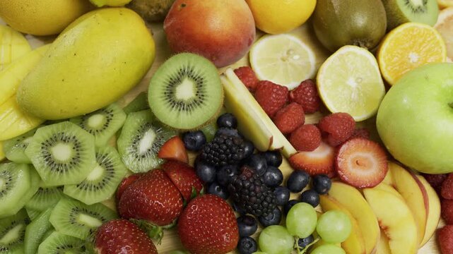 Sliced up kiwi, lemons, oranges and peaches with various other fruits in cluster - high shot