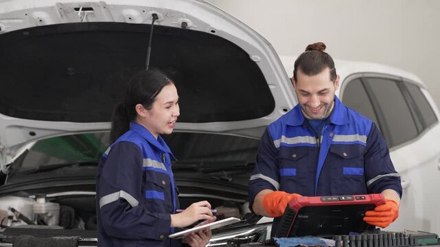 Auto mechanic technician using diagnostic tool for car repair in garage, inspecting vehicle engine during maintenance service workshop