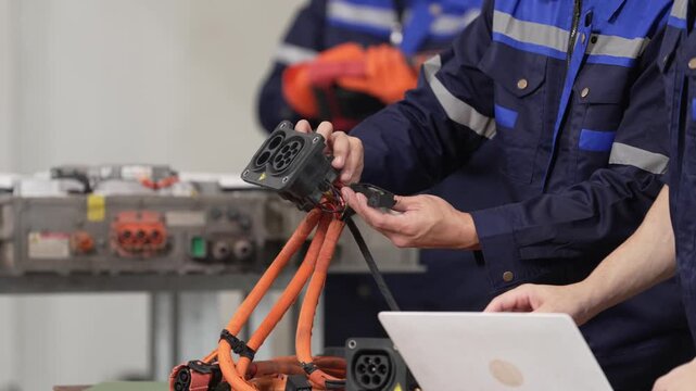 Technician laptop cable workshop uniform repair electric maintenance crew checking orange connector plug power machine part