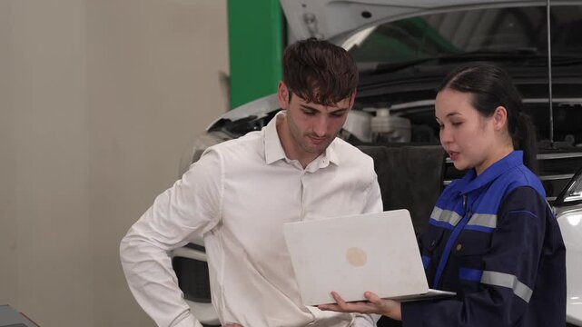 Auto repair mechanic with customer using laptop in garage consultation for vehicle service inspection diagnostic report workshop