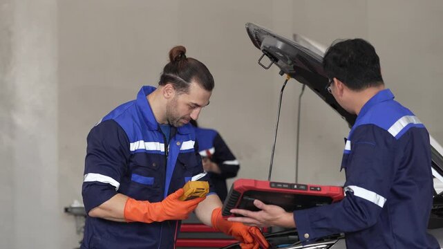 Mechanic technician diagnostic tool glove uniform workshop vehicle repair team checks engine near open hood during service inspection
