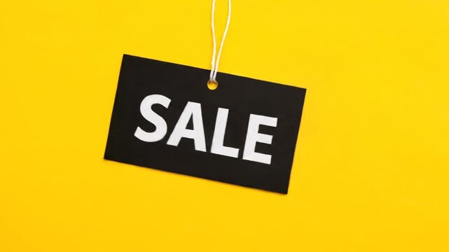 Black sale tag hanging on bright yellow background