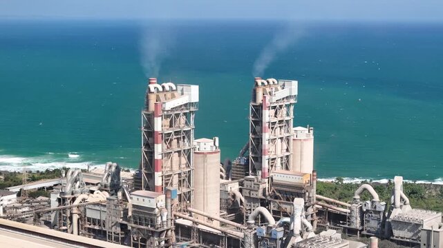 Drone panorama of a seaside cement factory, representing heavy industry, economic development, and modern construction supply.