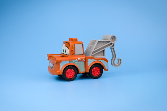 A Tow Mater toy from Disney Pixar Cars is shown from a side rear angle with its towing structure, brown bodywork, and red wheels against a light blue background on Jul 25, 2026 in Jakarta, Indonesia