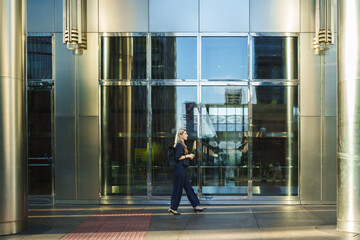 Woman walking confidently outside a contemporary office building, reflecting city life © pablo