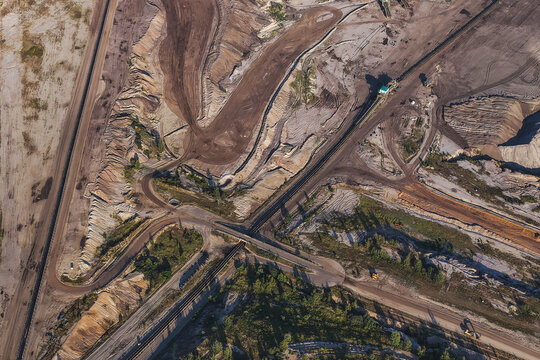 Aerial view of the lignite open cast mine Schleenhain showing extensive excavation patterns, dirt roads, industrial tracks, and sparse vegetation in Zwenkau, Saxony, Germany.