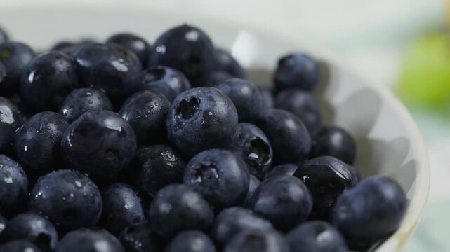 Wet, fresh blueberries in bowl - closeup panning shot